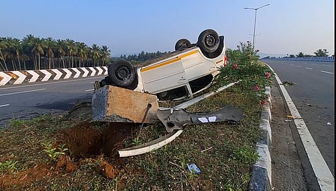 நத்தம் அருகே  சாலையின் நடுவில் இருந்த மின் கம்பத்தில் மோதி தலை குப்புற கவிழ்ந்து கிடக்கும் கார்.