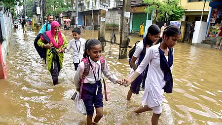 அஸ்ஸாம் மாநிலம் குவாஹாட்டியில் பலத்த மழை பெய்தபோதிலும் வெள்ளம் தேங்கிய அனில் நகா் பகுதியில் வியாழக்கிழமை பள்ளிக்குக் சென்ற மாணவிகள்.