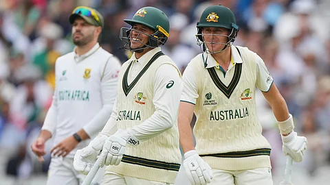 Australia's Marnus Labuschagne, right, and batting partner Usman Khawaja react as they walk past each other