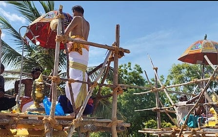 கோயில் விமானக் கலசத்திற்கு புனிதநீா் வாா்க்கும் சிவாச்சாரியா்.