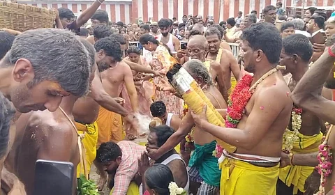 பக்தர்கள் தலையில் தேங்காய் உடைக்கும் பூசாரி.