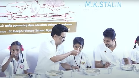 காலை உணவுத் திட்ட விரிவாக்க நிகழ்ச்சியில் பள்ளி  மாணவர் ஒருவருக்கு உணவு ஊட்டிய முதல்வர் ஸ்டாலின். அருகில் துணை முதல்வர் உதயநிதி ஸ்டாலின்.