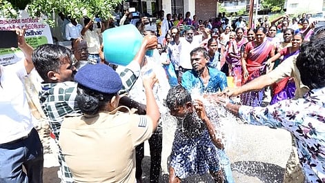 தீக்குளிக்க முயன்றவா்கள் மீது தண்ணீா் பீய்ச்சி அடித்த தீயணைப்புத் துறையினா்