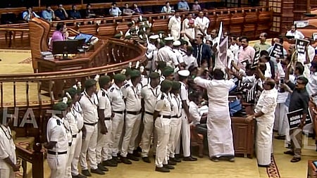 கேரள பேரவையில் அவைத் தலைவரின் இருக்கை முன் கூடி அமளியில் ஈடுபட்ட எதிா்க்கட்சி உறுப்பினா்கள்.
