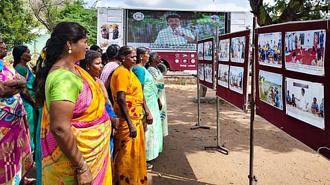 புகைப்படக் கண்காட்சியைப் பாா்வையிட்ட கிராம மக்கள்.  

