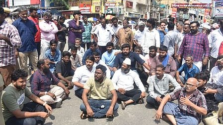 சாலை மறியல் ஈடுபட்ட கனி மாா்க்கெட் ஜவுளி வியாபாரிகள்.