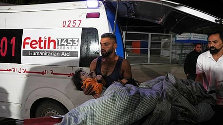 காஸாவில் இஸ்ரேல் தாக்குதலில் காயமடைந்த சிறுமியை டேய்ா் அல்-பாலா நகர மருத்துவமனைக்கு புதன்கிழமை அழைத்துவந்த பாலஸ்தீனா்.