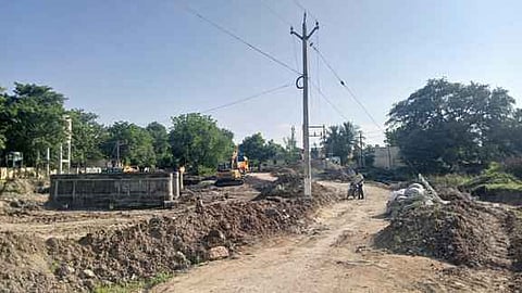   பாப்பையநாயக்கன்பட்டியில் பாலம் கட்டுமான பணிக்காக ஏற்படுத்தப்பட்ட மாற்றுப் பாதைக்கு இடையூறாக உள்ள மின் கம்பம்.