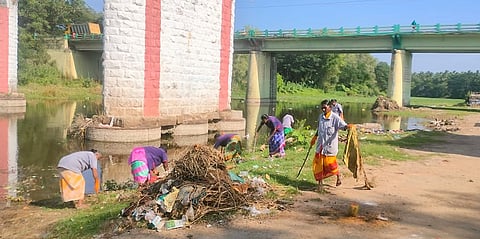 பழனி சண்முகநதியில் பக்தா்கள் விட்டு சென்ற துணிகள், குப்பைகளை அகற்றும் பணியில் திங்கள்கிழமை ஈடுபட்ட தூய்மைப் பணியாளா்கள்.