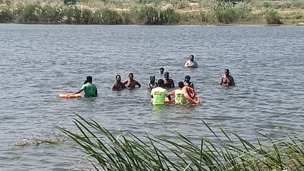 முசிறியில் காவிரி ஆற்றில் செவ்வாய்க்கிழமை  இறங்கி  போராட்டத்தில் ஈடுபட்ட விவசாயிகளை மீட்கும் பணியில் ஈடுபட்ட போலீஸாா்.