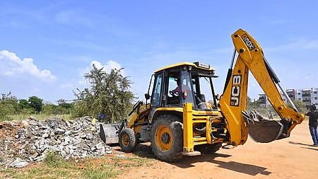 மாணவி பாலியல் வன்கொடுமை செய்யப்பட்ட பகுதியில் இருந்த புதா்கள், மண்மேடுகளை பொக்லைன் இயந்திரம் மூலம் அகற்றிய மாநகராட்சி ஊழியா்கள்.