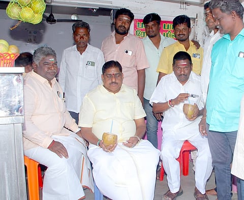 வியாபாரி அளித்த இளநீரைப் பருகும் புதுச்சேரி  உள்துறை அமைச்சா் ஆ. நமச்சிவாயம். 