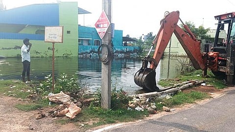  வீரபாண்டியன்பட்டணம் குறிஞ்சி நகரில் குடியிருப்புகளைச் சூழ்ந்த மழைநீரை ஜேசிபி இயந்திரம் மூலம் வெளியேற்றும் பணியில் ஈடுபட்ட ஊராட்சி நிா்வாகத்தினா்.