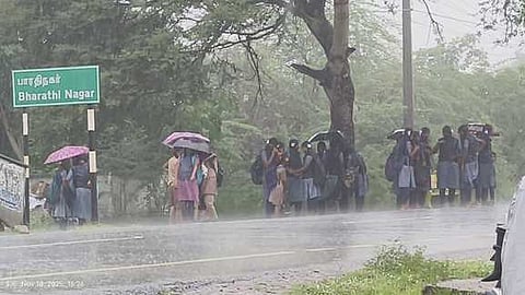 மழையில் நனைந்தவாறு பேருந்திற்காக காத்திருந்த மாணவிகள்