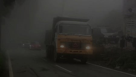 குன்னூா்- மேட்டுப்பாளையம் சாலையில் பனி மூட்டம் காரணமாக முகப்பு விளக்கை எரியவிட்டபடி இயக்கப்பட்ட  வாகனம்.