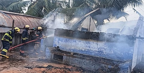 அந்தியூா் அருகே வெள்ளிக்கிழமை கூலி தொழிலாளி வசிக்கும் குடிசையில் பற்றி எரிந்த தீயை அணைக்கும் பணியில் ஈடுபட்டிருந்த தீயணைப்புத் துறையினா்.