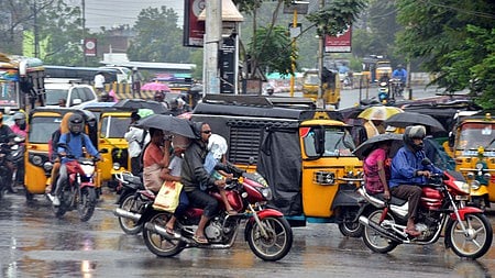மதுரை பெரியாா் பேருந்து நிலையம் பகுதியில் சனிக்கிழமை பெய்த மழையினூடே பயணித்தவா்கள். 