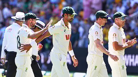 Australia's Mitchell Starc, centre, with teammates walks off the field after England all out during the second Ashes cricket test match between Australia and England in Brisbane, 