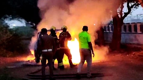 காா் மீது பற்றிய தீயை அணைக்கும் முயற்சியில் ஈடுபட்ட தீயணைப்புத் துறையினா்