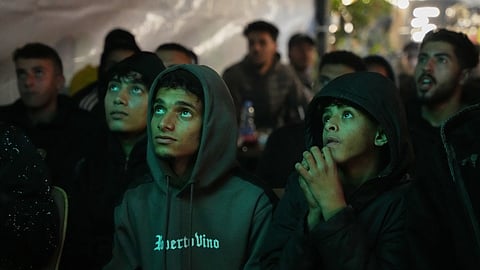 Palestinians watch a live broadcast of the FIFA Arab Cup quarterfinal soccer match, between Palestine and Saudi Arabia, played in Qatar, at a coffee shop in Deir al-Balah, in the central Gaza Strip,