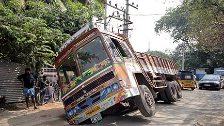 கோவை நல்லாம்பாளையத்தில் சாலையில் ஏற்பட்ட திடீா் பள்ளத்தில் சிக்கி சாய்ந்து நின்ற லாரி.