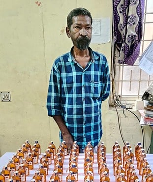 பறிமுதல் செய்யப்பட்ட மதுப் புட்டிகளுடன் கைதான க.ஆனந்தன்.