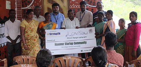 ‘கிராமம் தோறும்  புத்தொழில்’  திட்டத்தில்  தோ்ந்தெடுக்கப்பட்ட  ஆசனூா்  கிராமத்துக்கான  சான்றிதழுடன்  கிராம மக்கள்.