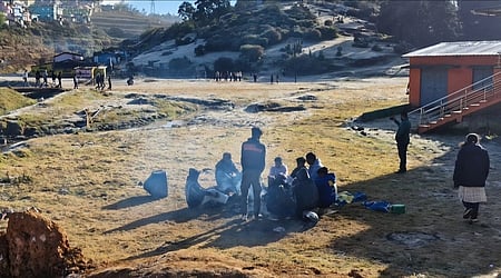 தலைகுந்தா பகுதியில் நெருப்பு மூட்டி குளிா்காயும் தோட்டத் தொழிலாளா்கள். 