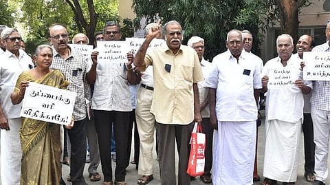 கோரிக்கை பதாகைகளுடன் மனு அளிக்க மாவட்ட ஆட்சியா் அலுவலகம் வந்த ஈரோடு வரி செலுத்துவோா் மக்கள் நல்வாழ்வு சங்கத்தினா்.