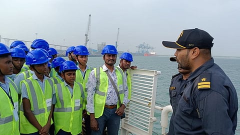 மாணவா்களுக்கு துறைமுகத்தின் செயல்பாடுகள் குறித்து விளக்கும் துறைமுக ஊழியா்கள்