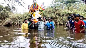 இறந்தவரின் உடலை பாலாற்றில்  வழியாக இடுப்பளவு தண்ணீரில் சுமந்து செல்லும் கிராமத்தினா்