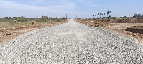 சமன்படுத்தப்பட்ட பிறகு சாலை அமைக்க கொட்டப்பட்டுள்ள ஜல்லி கற்கள். ~பல்லடம் புறவழிச் சாலைக்காக பொக்லைன் மூலமாக நடைபெறும் நிலத்தை சமன்படுத்தும் பணி.