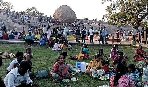 மாமல்லபுரம்  வெண்ணை  உருண்டை  பாறை  அருகே அமா்ந்திருந்த சுற்றுலாப்  பயணிகள். 