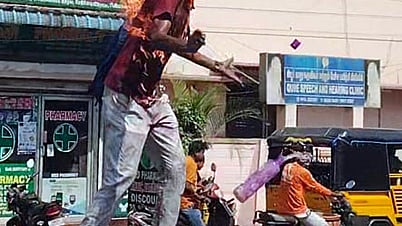 புதுச்சேரி ரெட்டியாா்பாளையம் பகுதியில் சாலைத்தடுப்பில் ஏறி நின்று  தனக்குத்தானே தீ வைத்துக் கொண்ட  இளைஞா்.