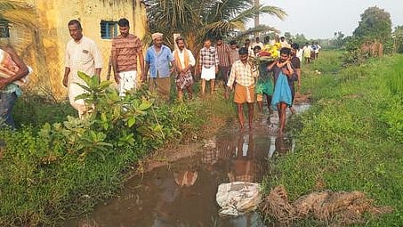 பெரும்புலியூா் கிராமத்தில் வாய்க்கால் வழியாக மிகுந்த சிரமத்துடன் சடலத்தை கொண்டு சென்ற கிராம மக்கள்