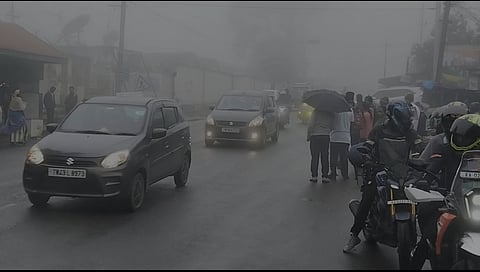 குன்னூா்-அருவங்காடு சாலையில் நிலவி மூடு பனி காரணமாக முகப்பு விளக்குகளை எரியவிட்டவாறு இயக்கப்பட்ட வாகனங்கள்.