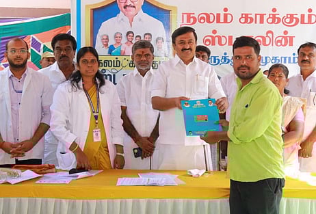 முகாமில் பயனாளி ஒருவருக்கு மருத்துவ காப்பீட்டுத் திட்ட அட்டை வழங்குகிறாா் அமைச்சா் மு.பெ.சாமிநாதன்.
