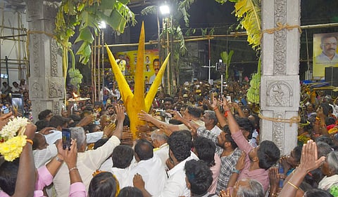  பழனி மாரியம்மன் கோயிலில் புதன்கிழமை அதிகாலை நடப்பட்ட திரிசூல வடிவிலான திருக்கம்பத்தை வழிபட்ட பக்தா்கள். 