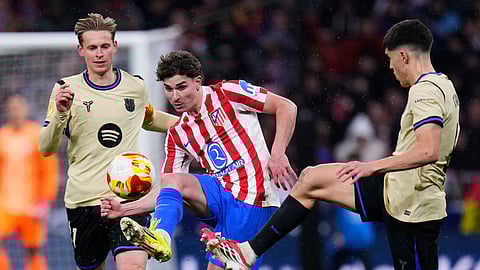 Atletico Madrid's Julian Alvarez, centre, challenges for the ball with Barcelona's Pau Cubarsi, right, and Frenkie de Jong during the Copa del Rey semifinal first leg soccer match between Atletico Madrid and Barcelona in Madrid, Spain, Thursday, Feb. 12, 2026. (AP Photo/Manu Fernandez)