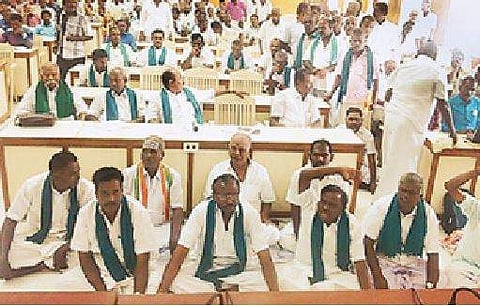 திருவாரூரில் நடைபெற்ற விவசாயிகள் குறைதீர் கூட்டத்தில் பேசுகிறார் மாவட்ட ஆட்சியர் இல. நிர்மல்ராஜ். கூட்டத்தில், தரையில் அமர்ந்து கோஷமிடும் விவசாயிகள். 