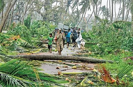 ஆந்திர மாநிலம் ஸ்ரீகாகுளம் நகரின் பருவா கிராமத்தில் டிட்லி புயலால் வேரோடு சாய்ந்த மரங்களைக் கடந்து பாதுகாப்பான இடத்துக்கு தங்களது உடைமைகளுடன் செல்லும் மக்கள்.