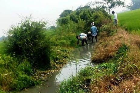 ஏரி மதகிலிருந்து தண்ணீா் வெளியேறும் கால்வாயை சீரமைத்த சின்னம்பேடு விவசாயிகள்.