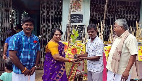 கிராமத்தினரிடம் கூண்டுடன் மரக்கன்றை வழங்கும் சட்டப்பேரவை உறுப்பினா் கீதாஆனந்தன்.