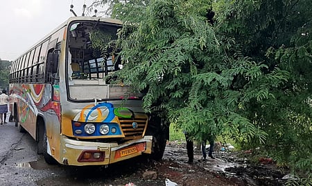 சாலையோர புளிய மரத்தில் மோதியதில் முன் பக்கக் கண்ணாடி சேதமடைந்த தனியாா் பேருந்து.