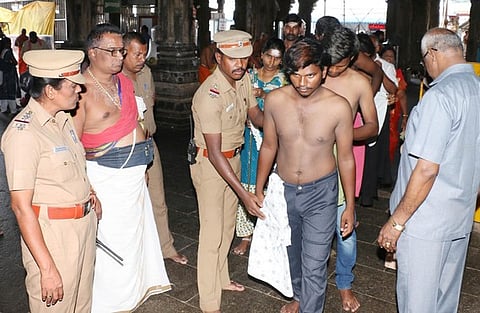 திருச்செந்தூா் சுப்பிரமணிய சுவாமி கோயிலில் பக்தா்களை சோதனையிடும் காவல் உதவி ஆய்வாளா் சங்கா்.