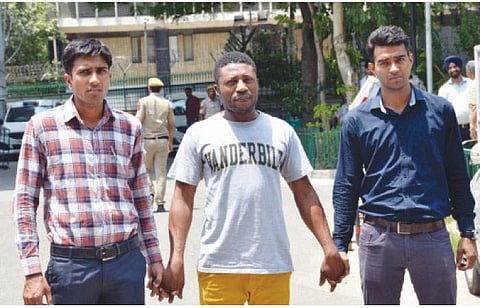 தில்லி போலீஸாரால் கைது செய்யப்பட்ட நைஜீரிய நாட்டைச் சேர்ந்த கில்பர்ட் ஒகோயே பெட்ரோ (நடுவில்).