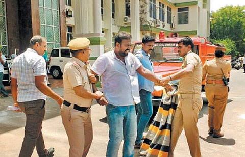 தீக்குளிக்க முயன்ற இளைஞரை தடுத்த போலீஸார் மற்றும் ஊர்க்காவல் படையினர்.