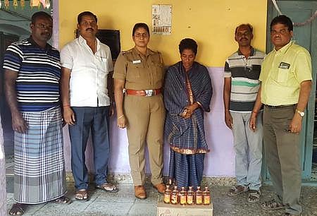 கைது செய்யப்பட்ட அனுசியா மற்றும் அவரிடமிருந்து பறிமுதல் செய்யப்பட்ட மதுப் புட்டிகள்.