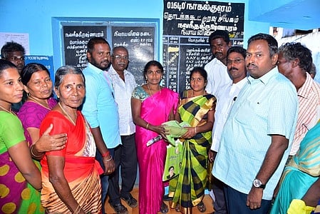 பொங்கல் பரிசு தொகுப்பினை வழங்குகிறாா் கூட்டுறவு சங்க தலைவா் பாா்வதி பரமசிவன்.