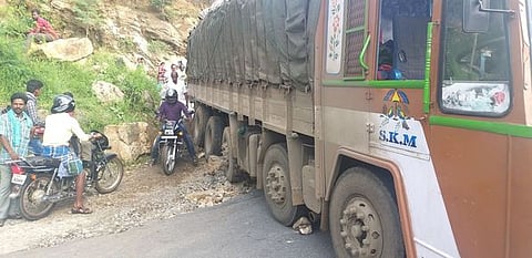குறுகிய சாலை வளைவில் திரும்ப முடியாமல் சிக்கி நிற்கும் டாரஸ் லாரி.